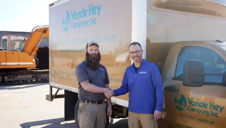 Two men shaking hands in front of Vande Hey Company truck, celebrating new partnership.